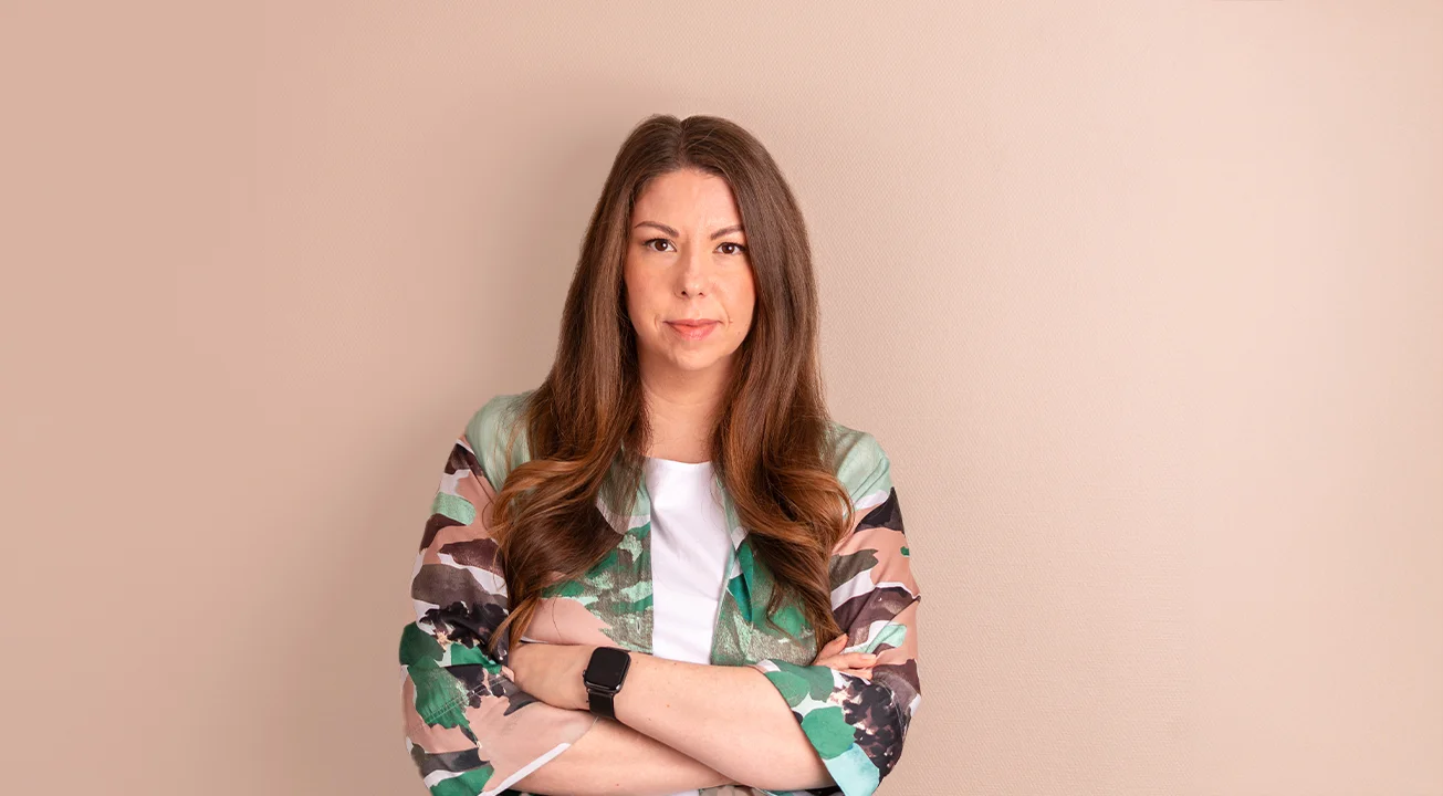 Orsi Imreh, ekspert på digital annonsering hos Frem Digital, står foran en beige vegg. Hun har på seg en mønstret jakke over en hvit topp, med armene i kors og et nøytralt uttrykk.