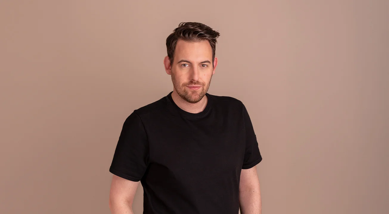 Bence Székely, Strategy Lead i Frem Digital, står foran en beige bakgrunn og ser inn i kameraet.